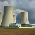 Concrete cooling towers of a nuclear power plant emitting steam under a cloudy sky